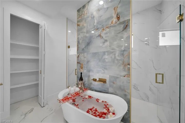 Bathroom featuring shower with separate bathtub, tile walls, and tile floors