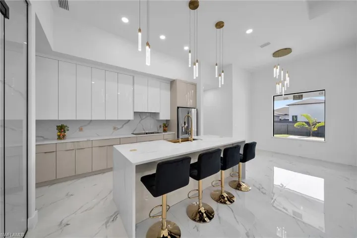 Kitchen with a kitchen breakfast bar, a center island with sink, decorative light fixtures, backsplash, and sink