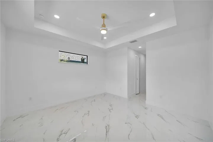 Tiled spare room with ceiling fan and a raised ceiling