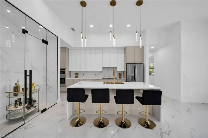 Kitchen featuring an island with sink, stainless steel appliances, a breakfast bar area, and pendant lighting