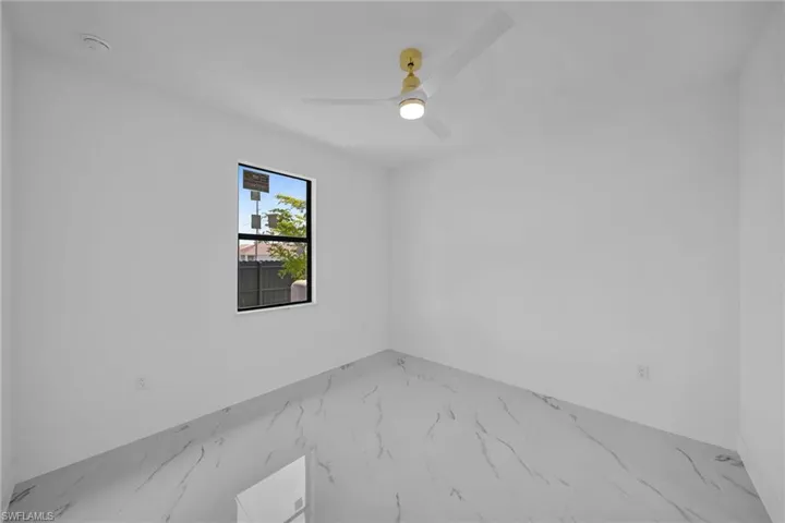Tiled spare room featuring ceiling fan