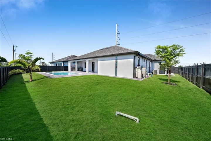 Rear view of property featuring a fenced in pool and a lawn