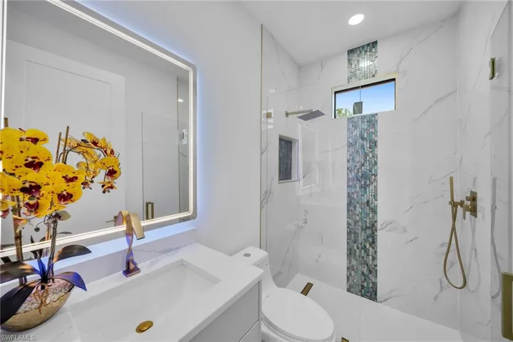 Bathroom featuring a tile shower, toilet, and vanity