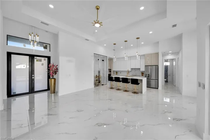 Kitchen with stainless steel refrigerator with ice dispenser, a tray ceiling, light tile flooring, and a kitchen island