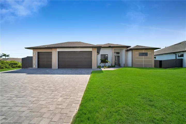 View of front facade featuring a garage and a front lawn