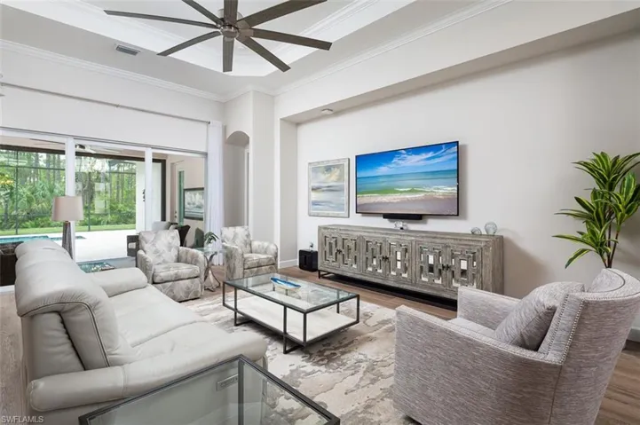 Living area with crown molding, wood finished floors, arched walkways, and a ceiling fan