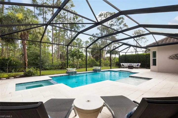 View of pool featuring a patio area, a pool with connected hot tub, outdoor lounge area, and a lanai