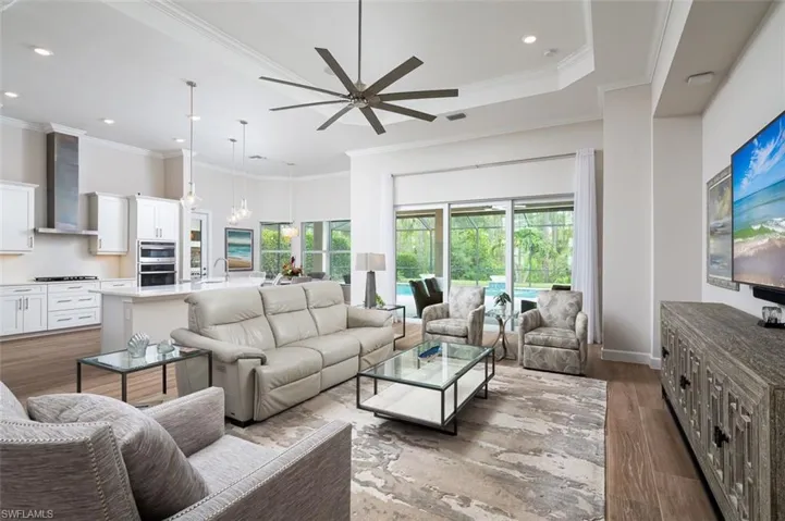 Living area with wood finished floors, ornamental molding, ceiling fan, and recessed lighting