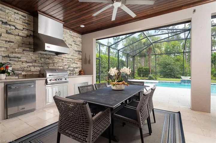View of patio featuring exterior kitchen, ceiling fan, an outdoor pool, a lanai, and outdoor dining space