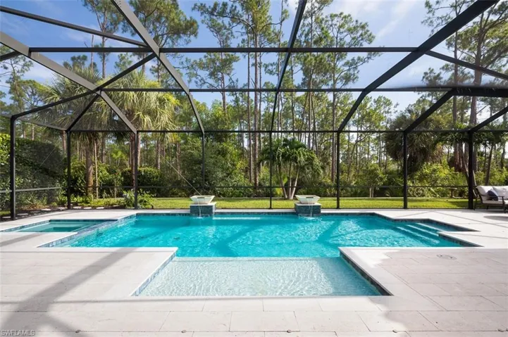 View of pool with a patio, a pool with connected hot tub, and glass enclosure