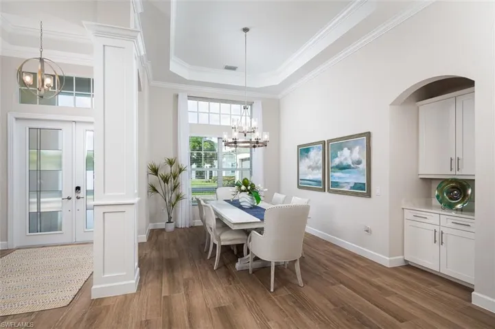 Dining room with a chandelier, french doors, ornamental molding, wood finished floors, and a tray ceiling