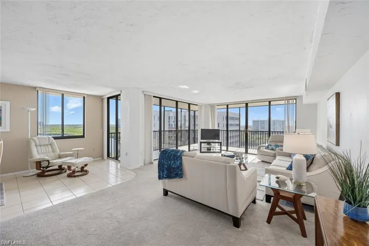 Carpeted living room with tile patterned flooring, a textured ceiling, and floor to ceiling windows