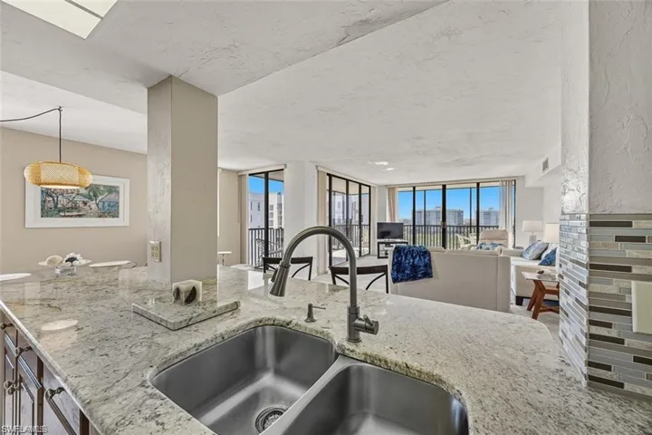 Kitchen with light stone countertops, decorative light fixtures, and open floor plan