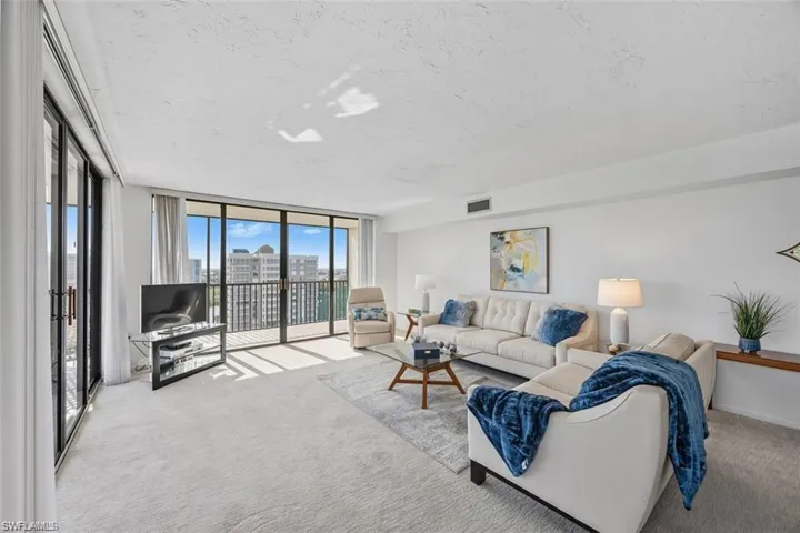 Living room with floor to ceiling windows, carpet flooring, and a textured ceiling