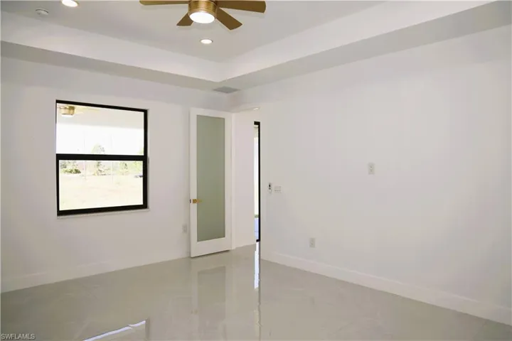 Tray ceiling with recessed lighting and a brass-finish ceiling fan