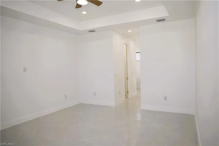 Recessed lighting, wood-finish ceiling fan, tray ceiling, tile flooring, and white baseboards