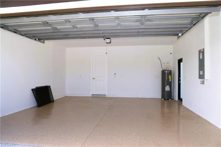 Spacious garage featuring epoxy-coated concrete flooring, overhead sectional garage door with automatic opener, and ample wall space for storage or workshop setup