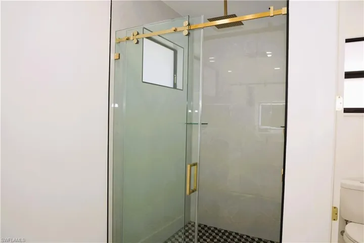 Glass-enclosed shower with gold-tone hardware