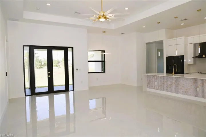 Modern kitchen featuring white cabinetry, a large center island with a decorative facade, integrated black appliances, and a walk-in pantry