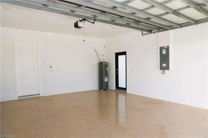 Spacious garage featuring a durable epoxy floor, white panel door, and ceiling-mounted garage door opener