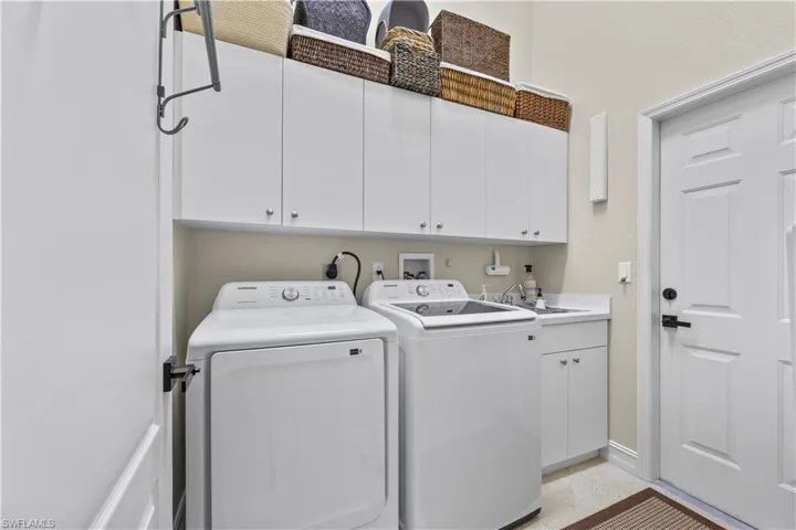 Clothes washing area featuring washer and clothes dryer, cabinets, and sink