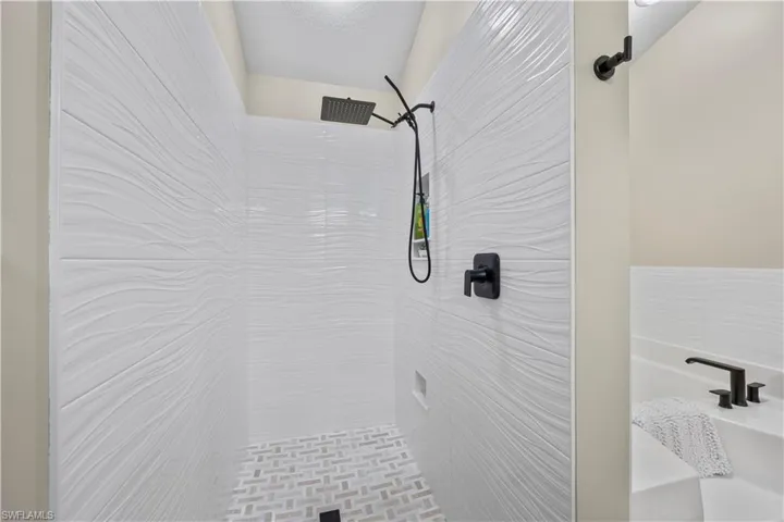 Primary bathroom shower featuring marble flooring.