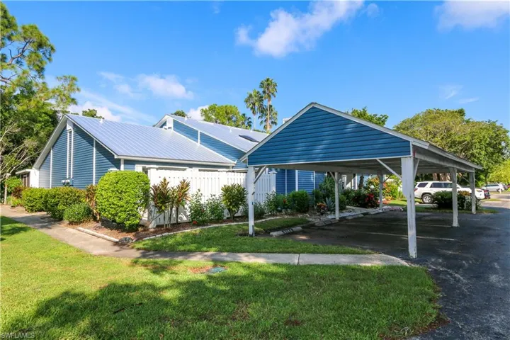 View of corner unit featuring a lawn and a carport