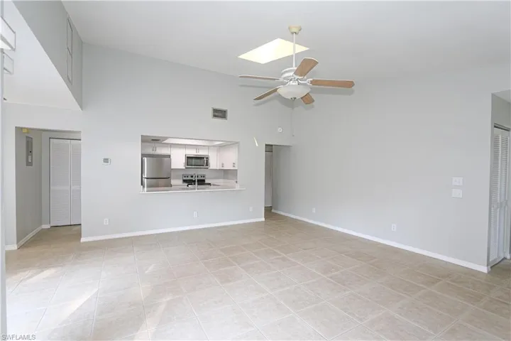 Great room with a towering ceiling, a skylight, ceiling fan and light tile patterned flooring