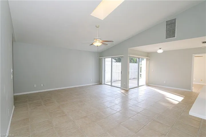 Great room featuring a skylight, high vaulted ceiling, ceiling fan and light tile patterned flooring