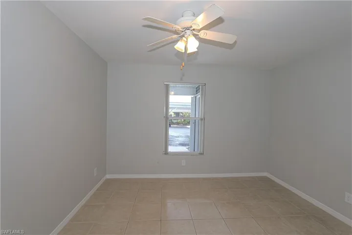 Guest bedroom with ceiling fan, light tile patterned flooring.