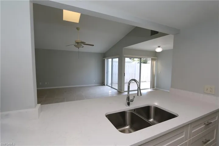Kitchen with tray ceiling, sink, light tile patterned floors and light quartz countertops