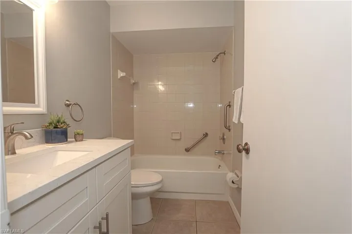 Guest bathroom featuring  shower. combination, quartz counter vanity, toilet, and light tile patterned floors