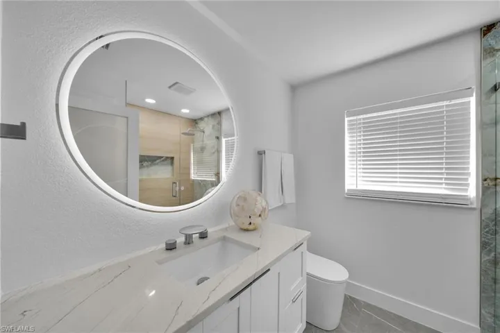 Bathroom featuring an enclosed shower, vanity, and toilet
