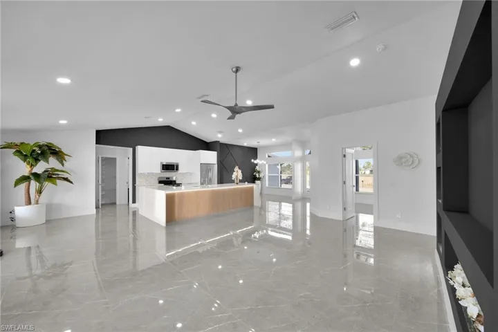 Kitchen featuring ceiling fan, stainless steel appliances, a kitchen island, decorative backsplash, and vaulted ceiling