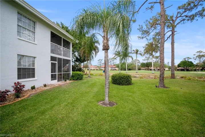 View of green lawn featuring a sunroom and a balcony