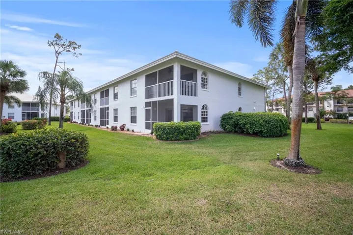 Back of property with a lawn, a sunroom, and stucco siding