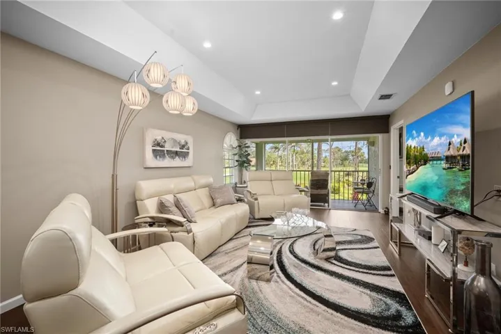Living room with wood finished floors, recessed lighting, and a raised ceiling