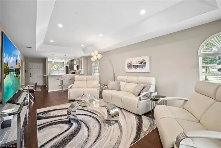 Living area featuring a tray ceiling, dark wood-style flooring, and recessed lighting