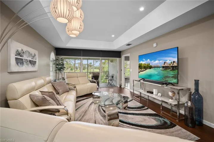 Living room featuring dark wood-type flooring, a raised ceiling, and recessed lighting