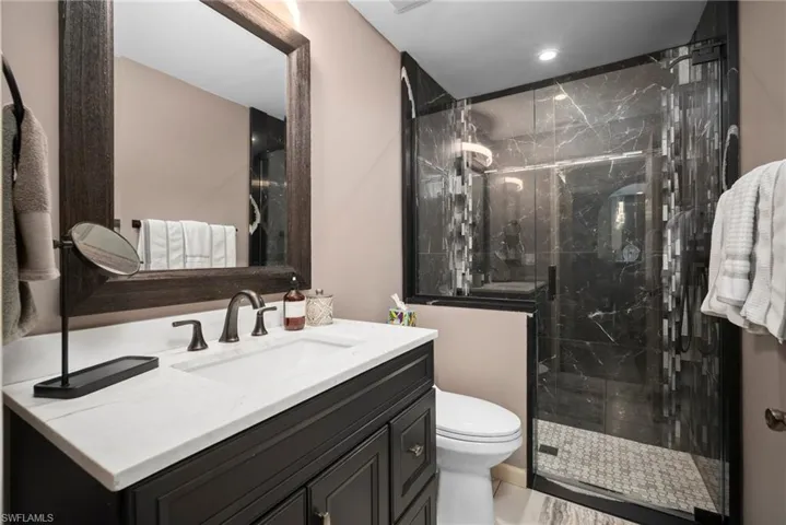 Bathroom featuring vanity and a marble finish shower