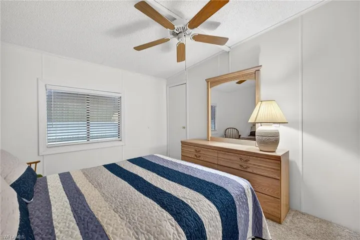 Bedroom featuring textured ceiling, light-toned wall panels, and neutral carpet flooring