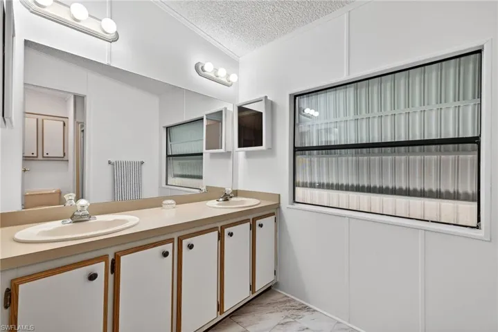 Bathroom vanity featuring dual oval sinks, a large wall-mounted mirror, and overhead strip lighting