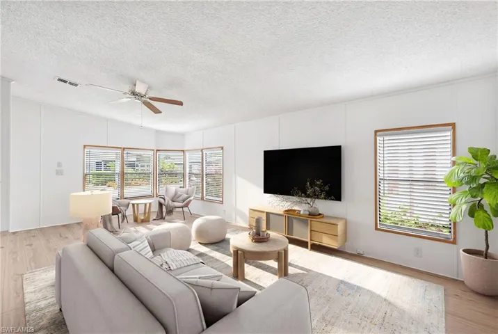 Virtually Staged Living area featuring wood-finish flooring, a ceiling fan with light fixture, and white wall paneling