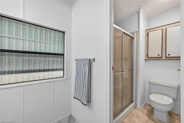 Bathroom featuring a glass-enclosed shower, white toilet, and built-in upper cabinetry