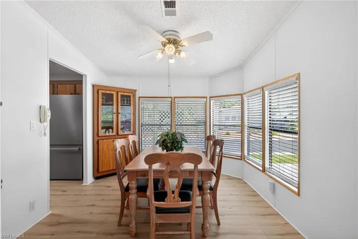 Dining area with light wood-finish flooring and multiple windows featuring blinds