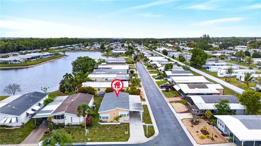 Waterfront property featuring a paved driveway, mature trees, and a spacious front yard