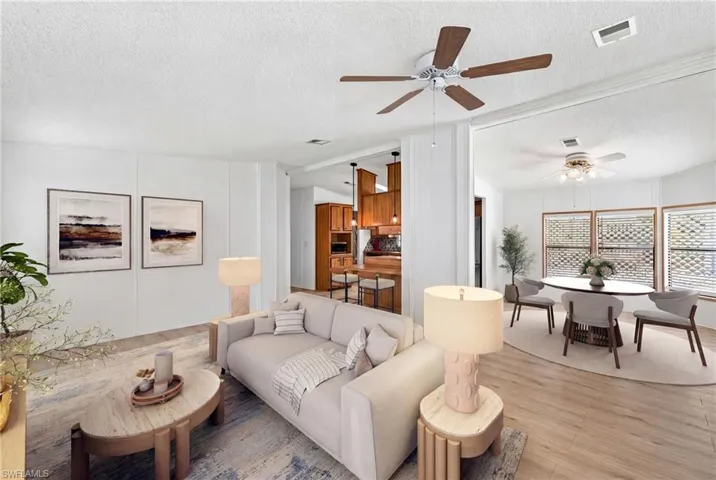 Virtually Staged Spacious living area featuring wood-finish flooring, a ceiling fan, and white paneled walls
