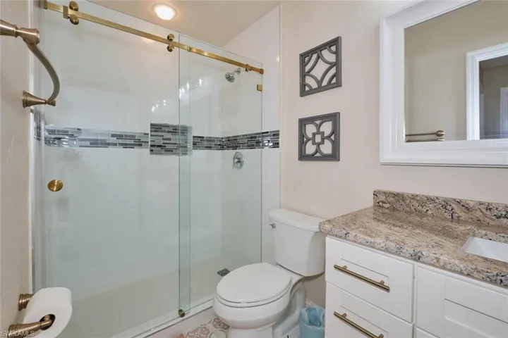 Bathroom featuring vanity, a shower with shower door, and toilet