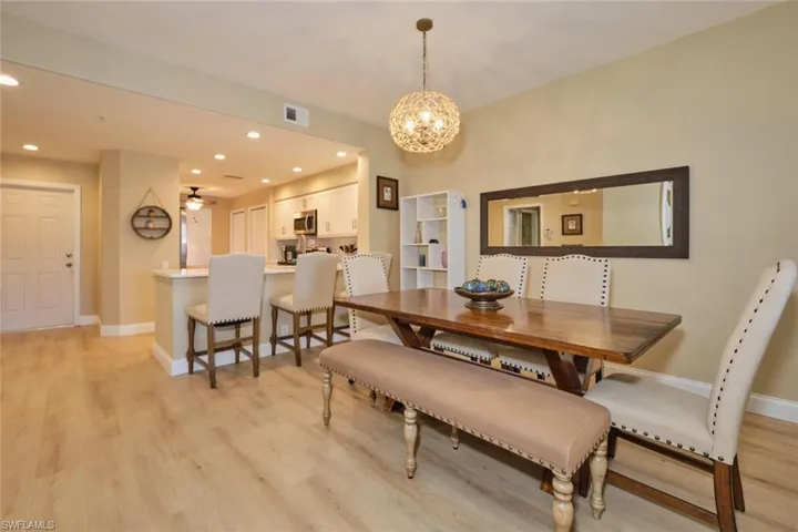 Dining room with light hardwood / wood-style floors and ceiling fan with notable chandelier