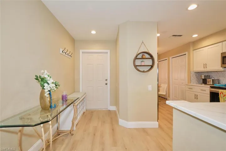 Kitchen with white cabinets, light hardwood / wood-style flooring, decorative backsplash, and appliances with stainless steel finishes